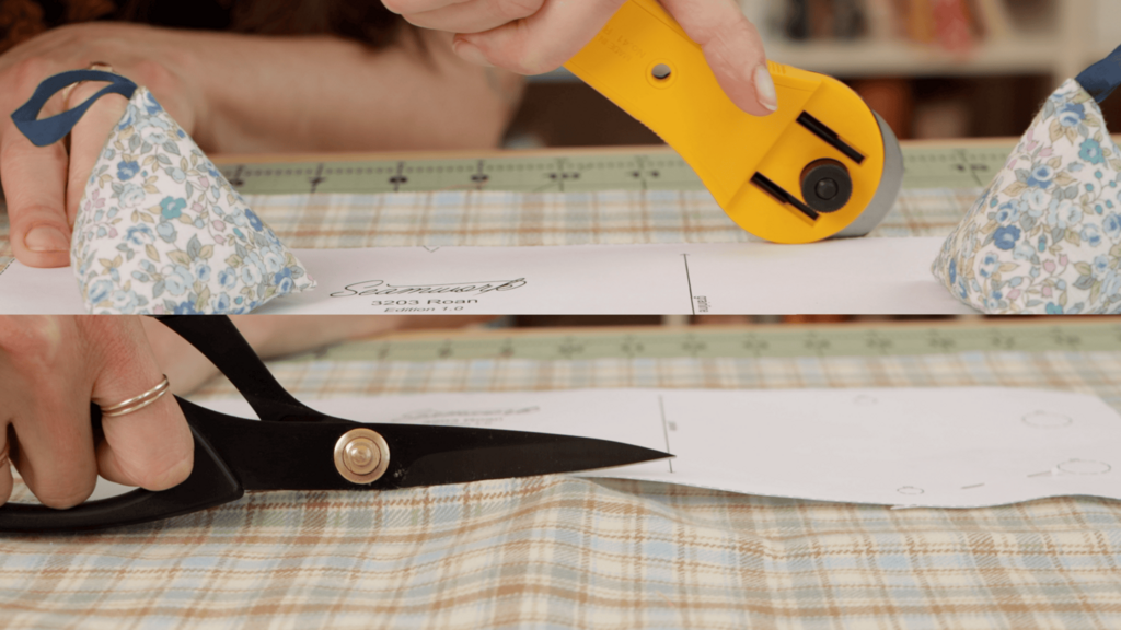Rotary cutter cutting through flannel on a cutting mat with pattern weights